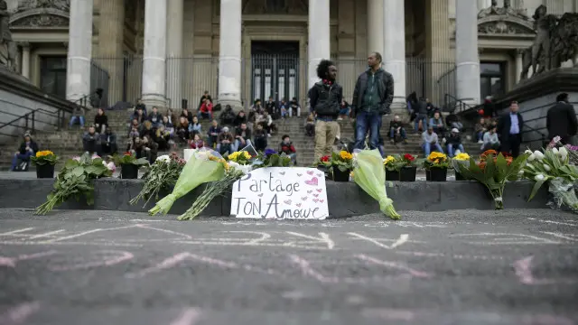 Люди приносят цветы в центр Брюсселя в память о жертвах теракта. Надпись на плакате: "Поделись любовью"