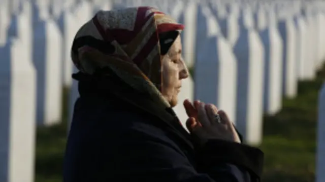 En esta foto del 20 de marzo de 2016, Fadila Efendic reza cerca de las tumbas de su esposo e hijo que murieron en la guerra de Bosnia.