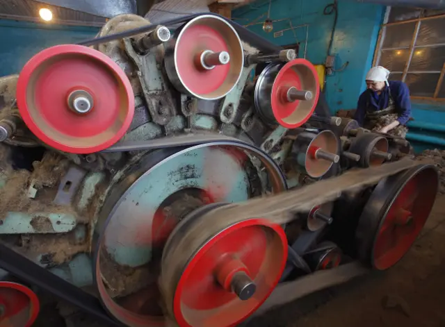 Женщина в Костромской области обслуживает старый станок для производства войлока