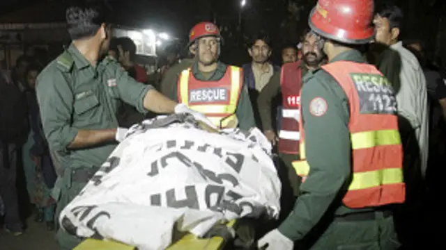 Grupos de rescate sacan un cadáver cubierto con una sábana sobre una camilla 