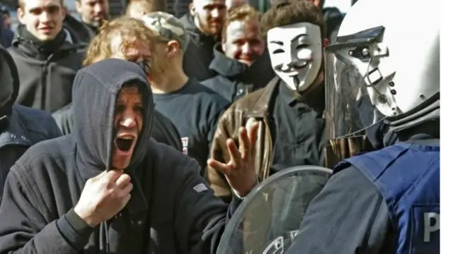 مظاہرے میں ملوث کئیوں نے بالکلاواز اور گمنام ماسک پہننے ہوئے تھے اور بہت سے ان میں سے نے کالے کپڑے پہننے ہوئے تھے