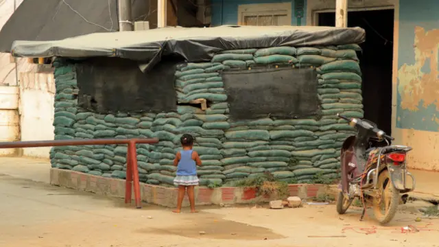 Niña frente a pila de bolsas de arena de estación de policía de La Gabarra