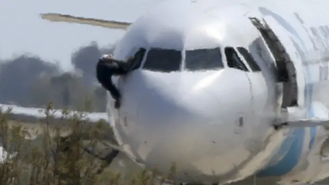 Một người cố trèo khỏi cửa buồng lái máy bay