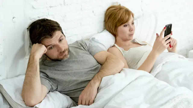 Pareja en la cama con el celular