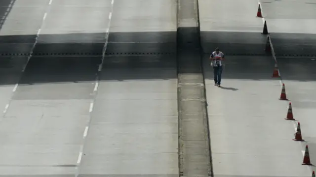 Hombre en carretera sin coches (foto de archivo)