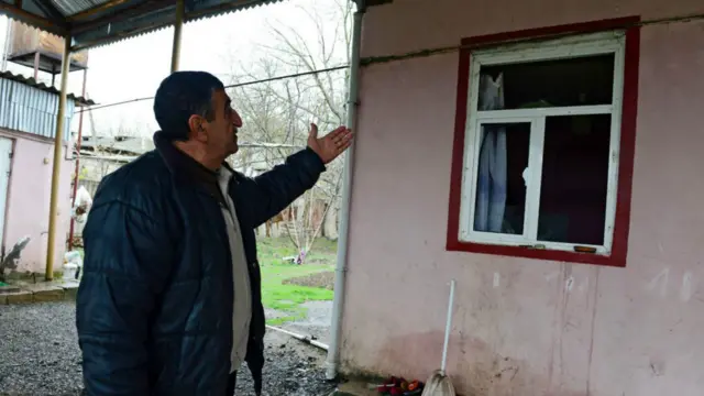 Житель азербайджанского города Тертер показывает на разрушения в своем доме