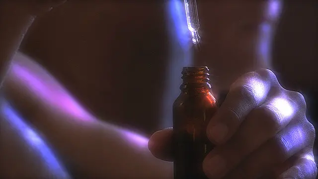 Mano con un pomo de droga líquida y un gotero