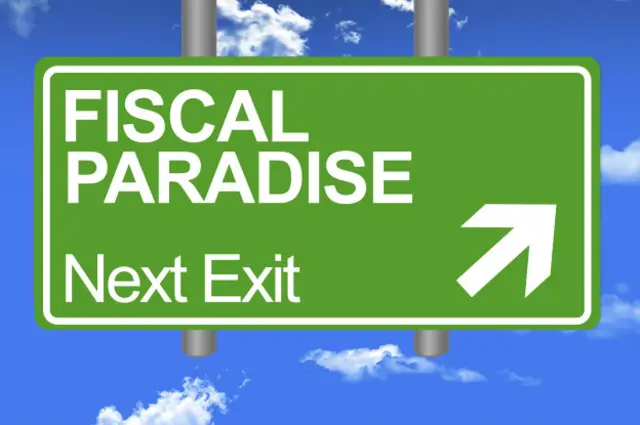 "Paraíso fiscal - Próxima salida", dice el cartel en el cielo, pues en inglés, el idioma de los negocios, también se le llama "tax haven": remanso de impuestos.