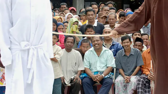 Hukum cambuk di Aceh dilakukan di hadapan warga.