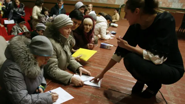 Переселенці з Донбасу заповнюють форми на соціальну допомогу у центрі тимчасового розташування в Ростовській області. Грудень 2014 року
