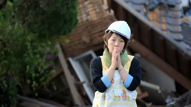 一名居民在倒塌的房屋前