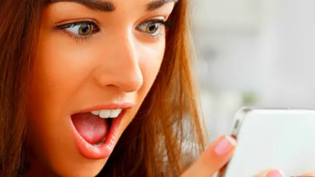 Una joven mirando sorprendida su teléfono