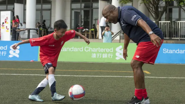 巴恩斯(右)指导一名少年足球学员