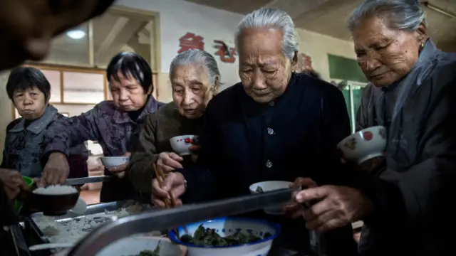Ancianas chinas se sirven comida en una residencia para mayores