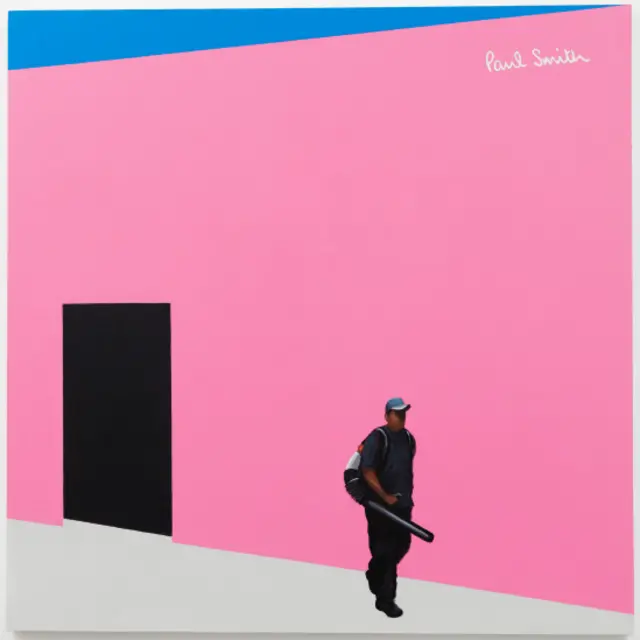 Un hombre con una máquina de recoger hojas delante de una tienda cara en Los Ángeles