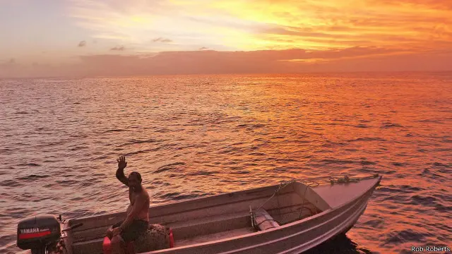 Dalam hitungan menit, sebuah perahu aluminium penuh lecet menghampiri kami dari dalam laguna yang tersembunyi. Sang pengemudi mematikan mesin tempel dan mendekati buritan kami.