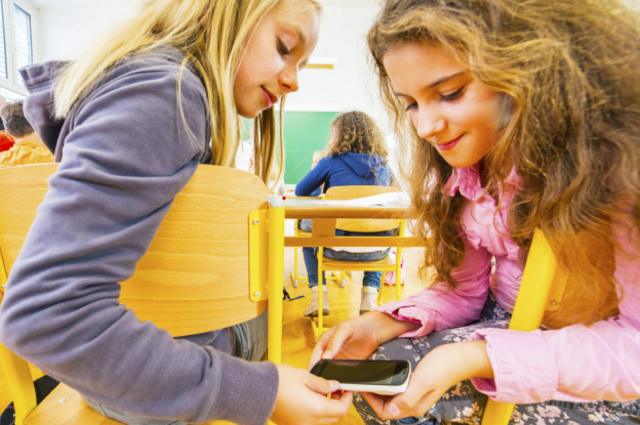 Dos niñas ven un celular durante una clase en la escuela