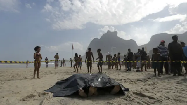 Dos cuerpos de personas muertas por la caída de una ciclovía yacen en una playa de Rio de Janeiro, Brasil.