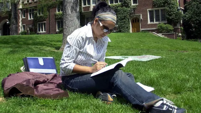 Una estudiante sobre el césped del campus