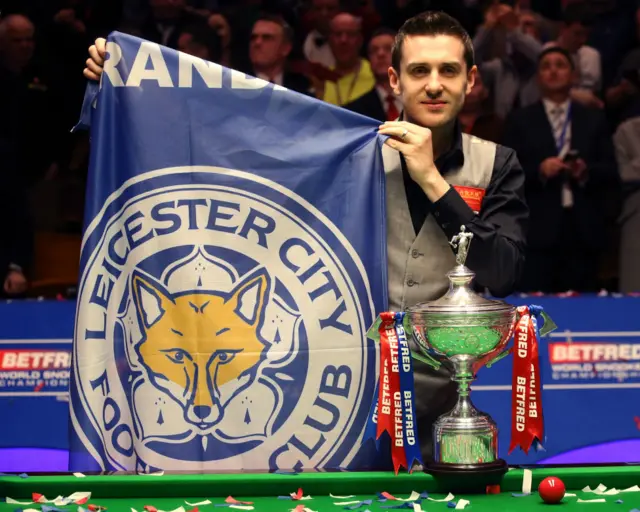 塞尔比手持莱斯特城足球俱乐部会旗与斯诺克世锦赛奖杯合照（2/5/2016）