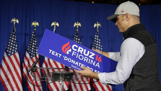 Un hombre retira el cartel de Ted Cruz y Carly Fiorina