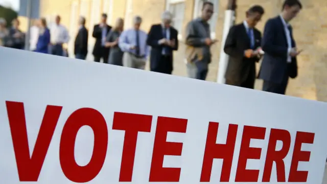 Un cartel ante una fila de votantes