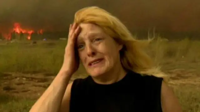 سيدة تبكي والنيران تلتهم منزلها وقد أمرت سلطات إقليم ألبرتا بإجلاء 88 ألف نسمة هم كل سكان فورت ماكموري وإعلان حالة الطوارئ