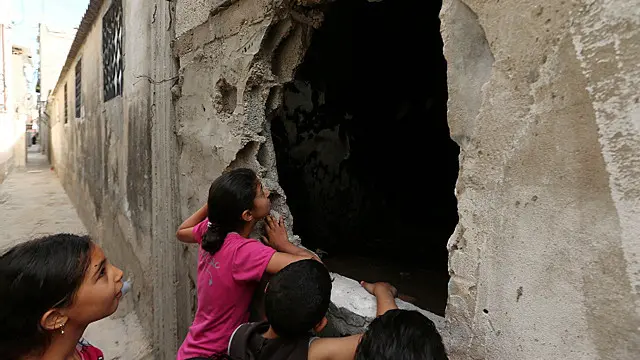 أطفال فلسطينيون ينظرون إلى المنزل الذي شهد موت ثلاثة أطفال احتراقا