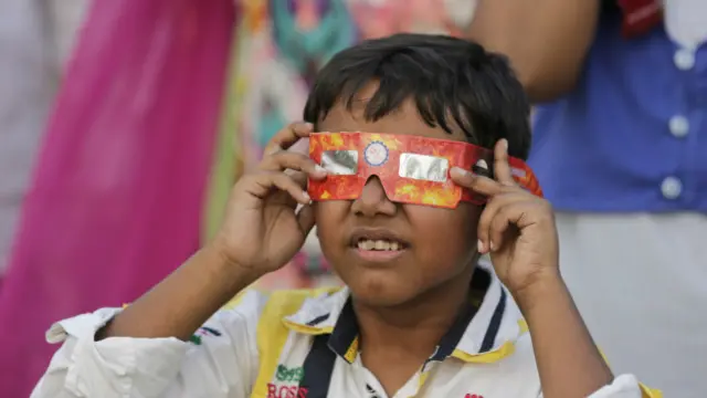 Niño tratando de observar el mordisco de Mercurio