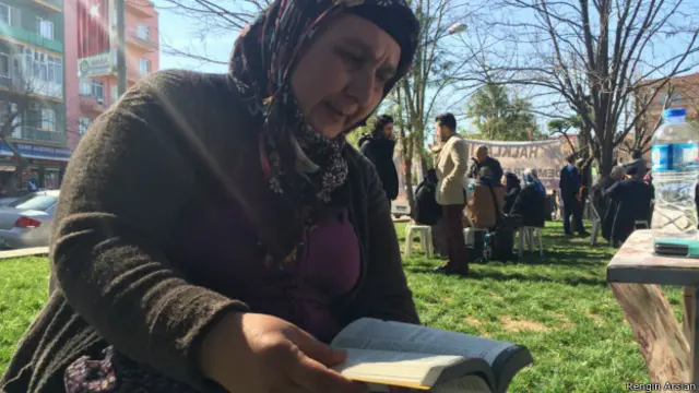 Eşi Soma'da ölen Gülizar Sav, duruşma arasında İş Cinayetleri Almanağı'nı okuyor.