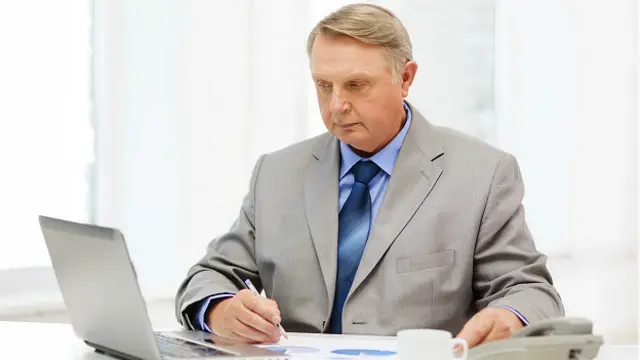 Пожилой бизнесмен перед ноутбуком