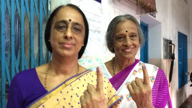 कोच्चि के एक मतदान केंद्र पर मतदान के बाद स्याही लगी ऊंगली दिखातीं मतदाता.