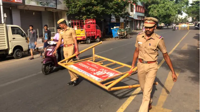 पुलिसकर्मी बेरीकेड ले जाते हुए.