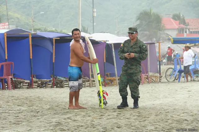 Surfista junto a un militar en Canoa