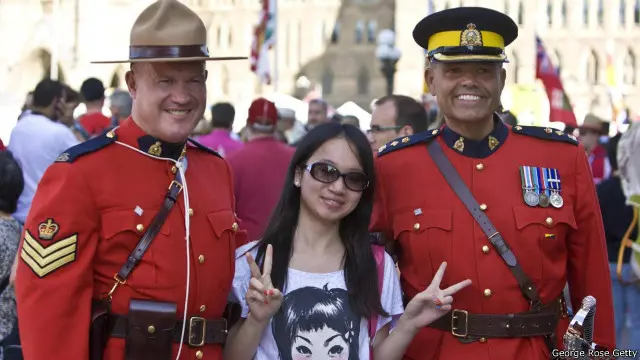 Dua anggota kepolisian Kanada dan seorang turis saat merayakan sebuah acara kenegaraan.