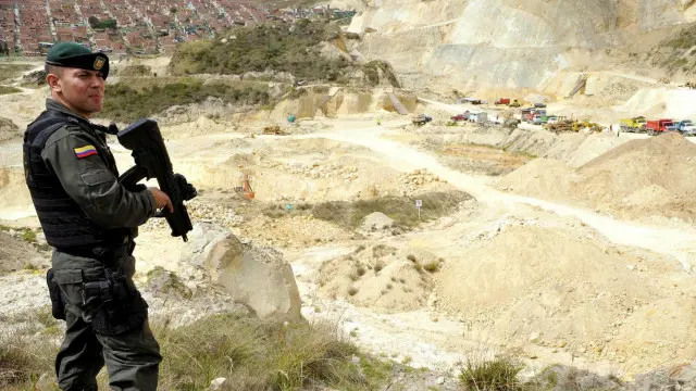 أدى الطلب على الرمل إلى بروز عمليات تنقيب واستخراج غير شرعية لهذه المادة. هنا يقف شرطي مسلح لحراسة موقع للرمال بالقرب من بوغوتا، كولومبيا. 