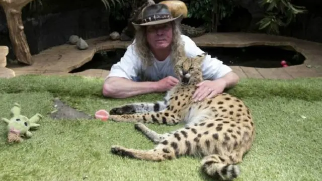 إيان نيوباي إلى جانب واحدة من القطط الأفريقية التي يقتنيها بمنزله.