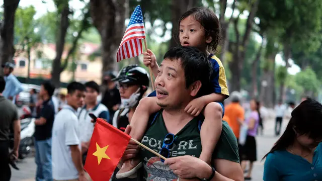 Вьетнамец с дочерью на плечах и с флажками