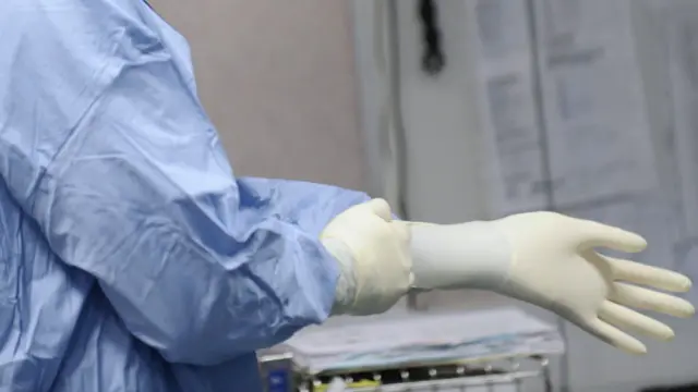 Un médico poniéndose los guantes quirúrgicos