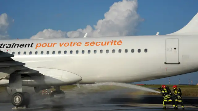 Bomberos sofocando un incendio en el exterior de un avión