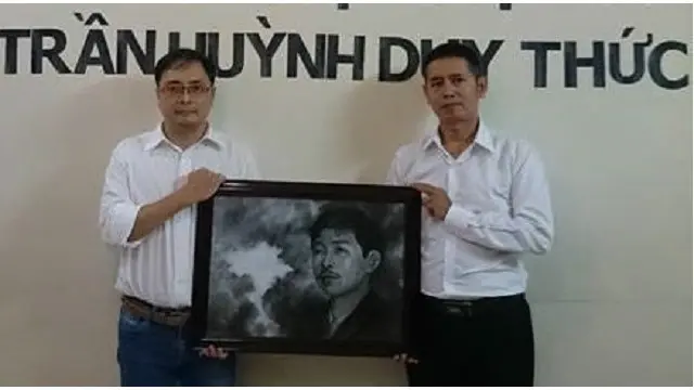 Hai cựu tù chính trị Lê Công Định và Lê Thăng Long cầm ảnh ông Trần Huỳnh Duy Thức