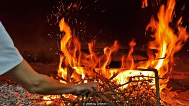 纳瓦罗在烹制海鲜饭的过程中会经常把手移到火的附近(图片来源:Matthew Bremner)