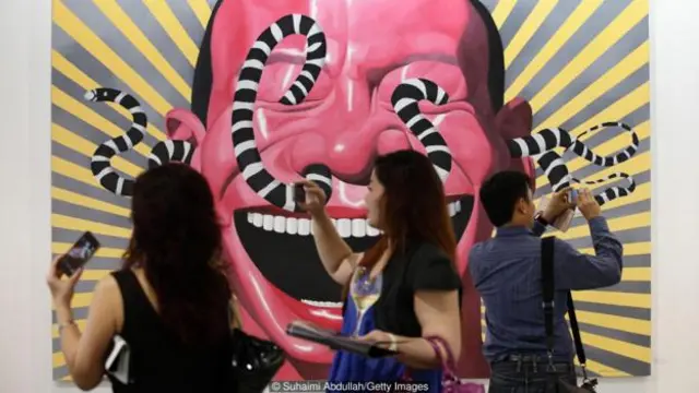 Người tham quan ngắm tác phẩm ‘Con rắn’ của Yue Minjun của Trung Quốc tại Art Stage Singapore (Ảnh: Suhaimi Abdullah/Getty Images)