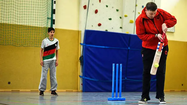 د جرمني د کریکټ فدراسیون منیجر برېن مانټل وايي 'دا لېونتوب دی!'. هره ورځ دی د کډوالو او ټولنیزو کارکوونکو غوښتنلیکونه ترلاسه کوي چې ګني دوی ته نوې ډلې جوړې کړي. جرمني د کډوالو د کړکېچ له کبله ډوبېدونکی دی: