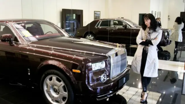 一位購物者端詳一輛售價800萬元人民幣的勞斯萊斯幻影轎車