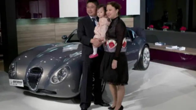 在上海百萬富翁展上，一個富裕的中國家庭站在一輛跑車旁拍照