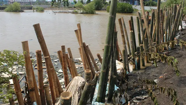 Pasir, karung pasir, dan bambu digunakan sementara untuk menahan air di lokasi yang jebol.