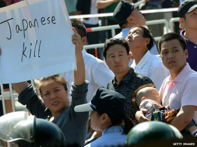 در جریان اعتراضات سال ۲۰۱۲، زنی یک پلاکارد ضد ژاپنی را بالای سر نگاه داشته است