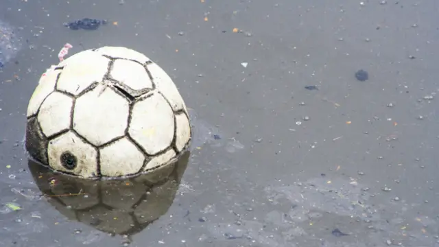 Футбольный мяч в грязной воде