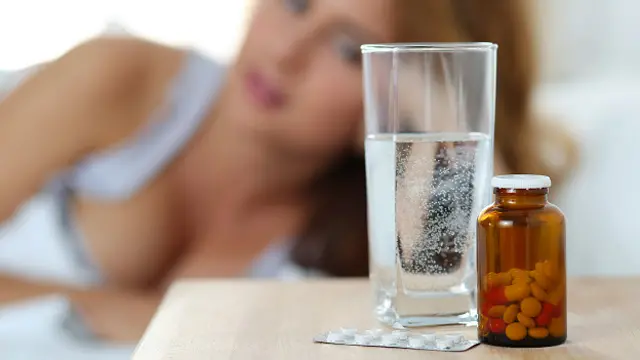 Стакан воды и лекарства на тумбочке у кровати